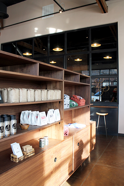 A retail display case made in the mid-century industrial modern style. Bags of coffee and mugs line the shelves